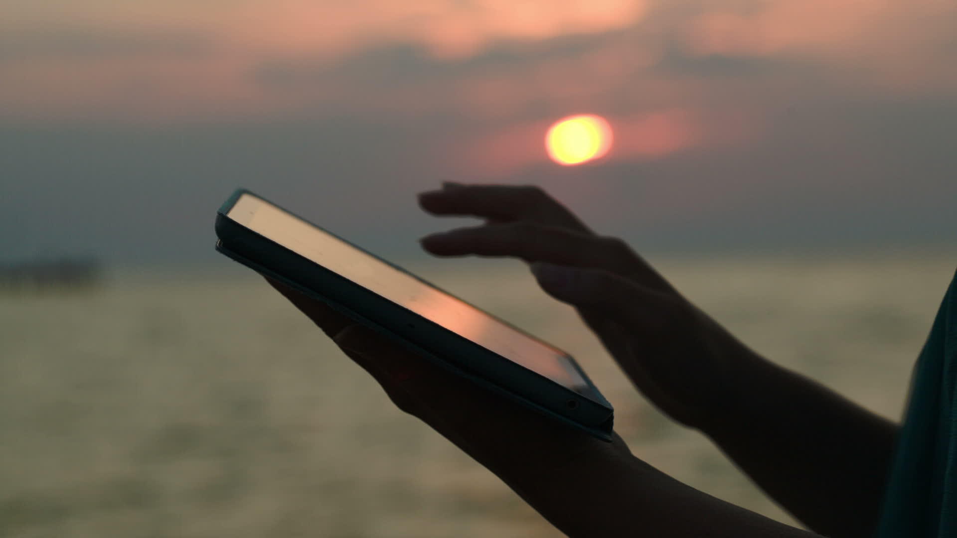 日落时在海滩上使用触摸板视频的预览图