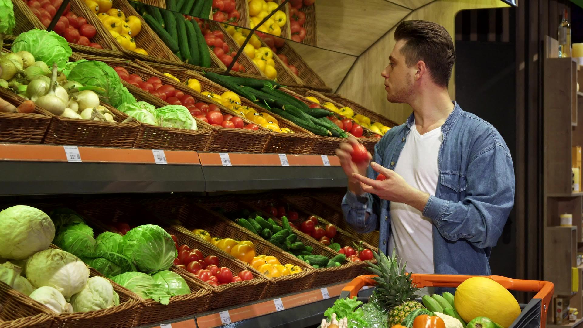 男人从超市的架子上拿番茄和黄瓜视频的预览图