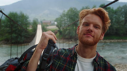 微笑的徒步旅行者在河桥肖像上拍照视频的预览图