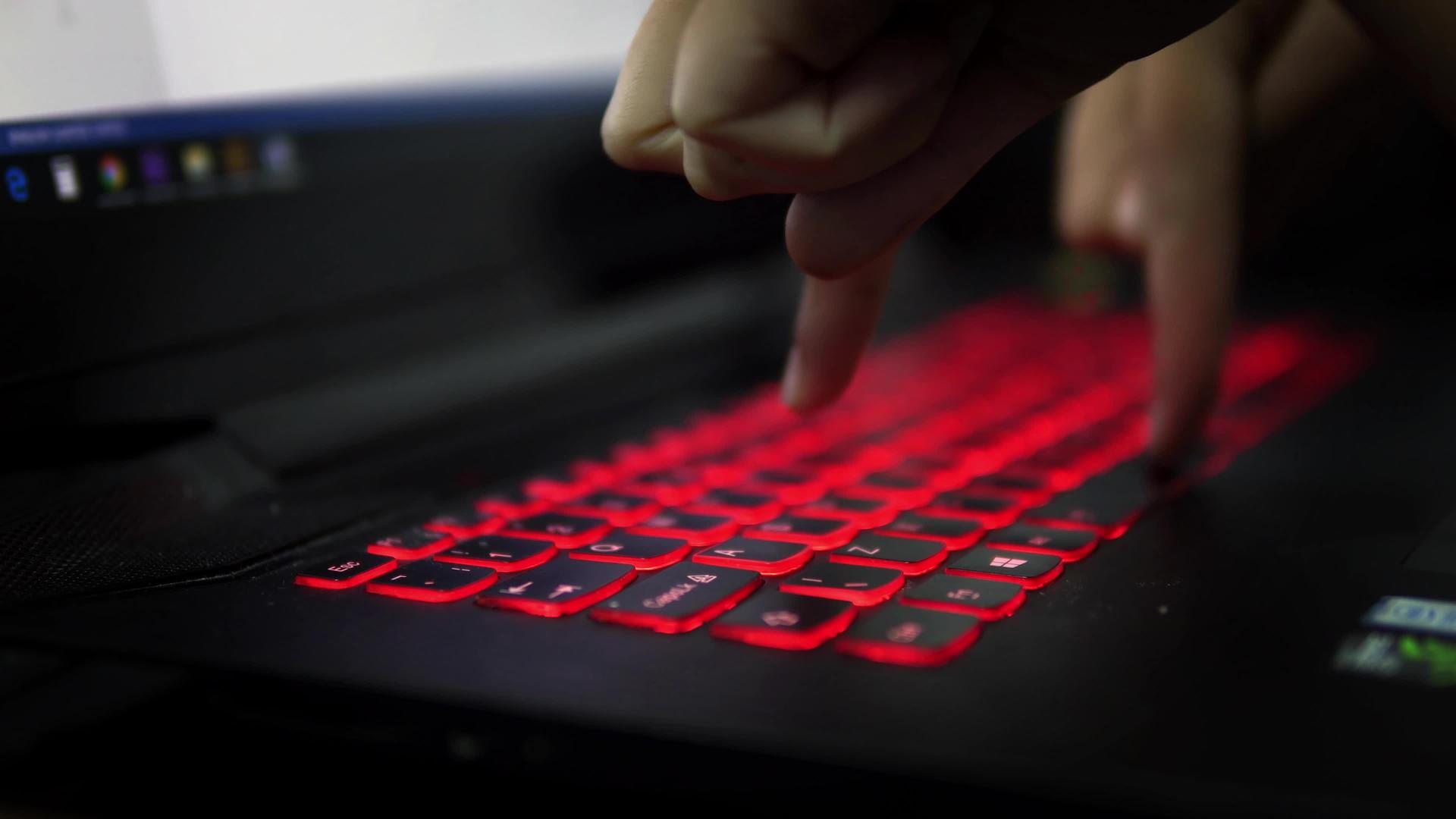 在黑暗中用两个手指在笔记本电脑上用红色键盘打字视频的预览图