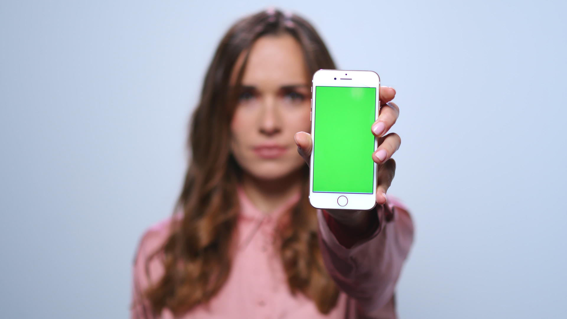 在演播室用绿色屏幕显示智能手机的女性视频的预览图