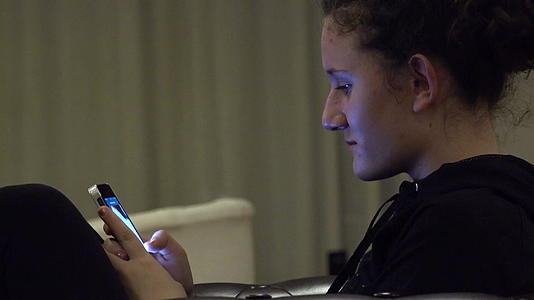 智能手机女孩使用手机应用程序躺在酒店大堂的沙发上视频的预览图