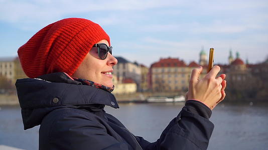 年轻的年轻人戴着红帽子在普莱格切奇观光用智能手机微笑拍照视频的预览图