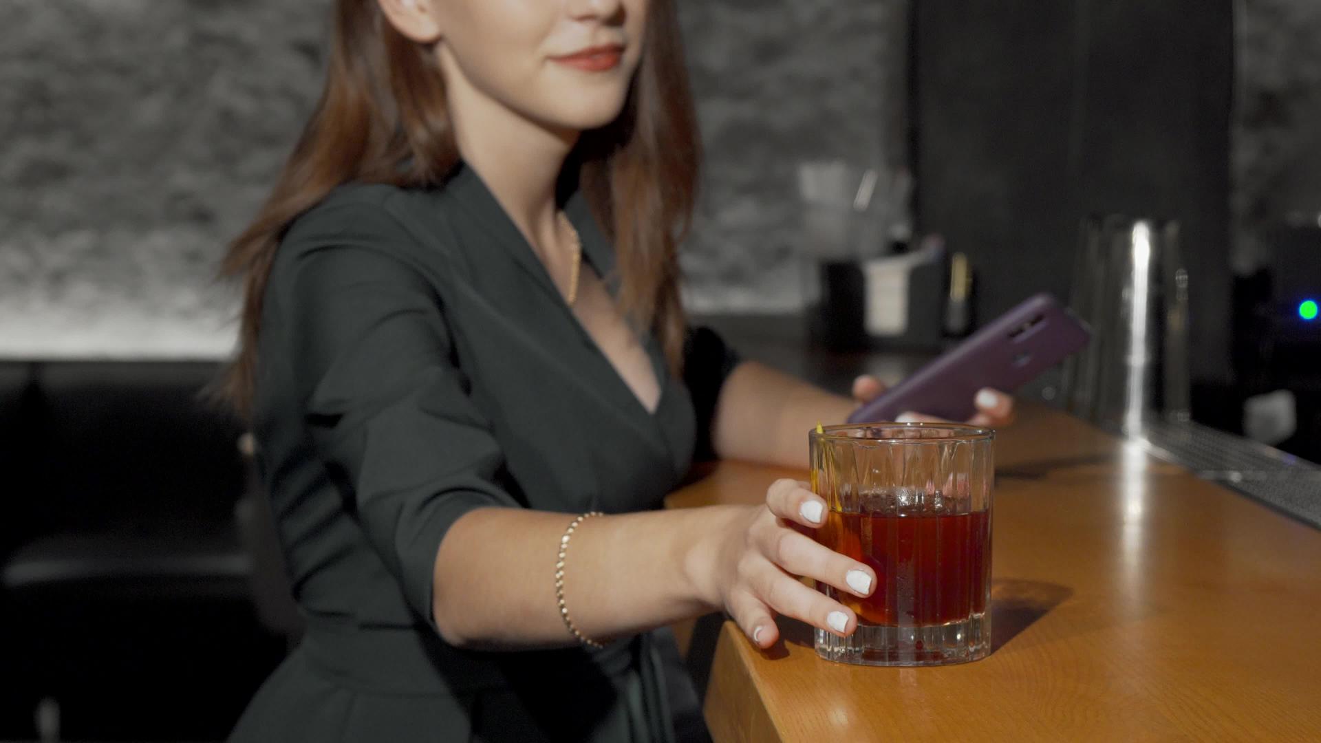 一个从酒吧柜台拿鸡尾酒杯的女人视频的预览图