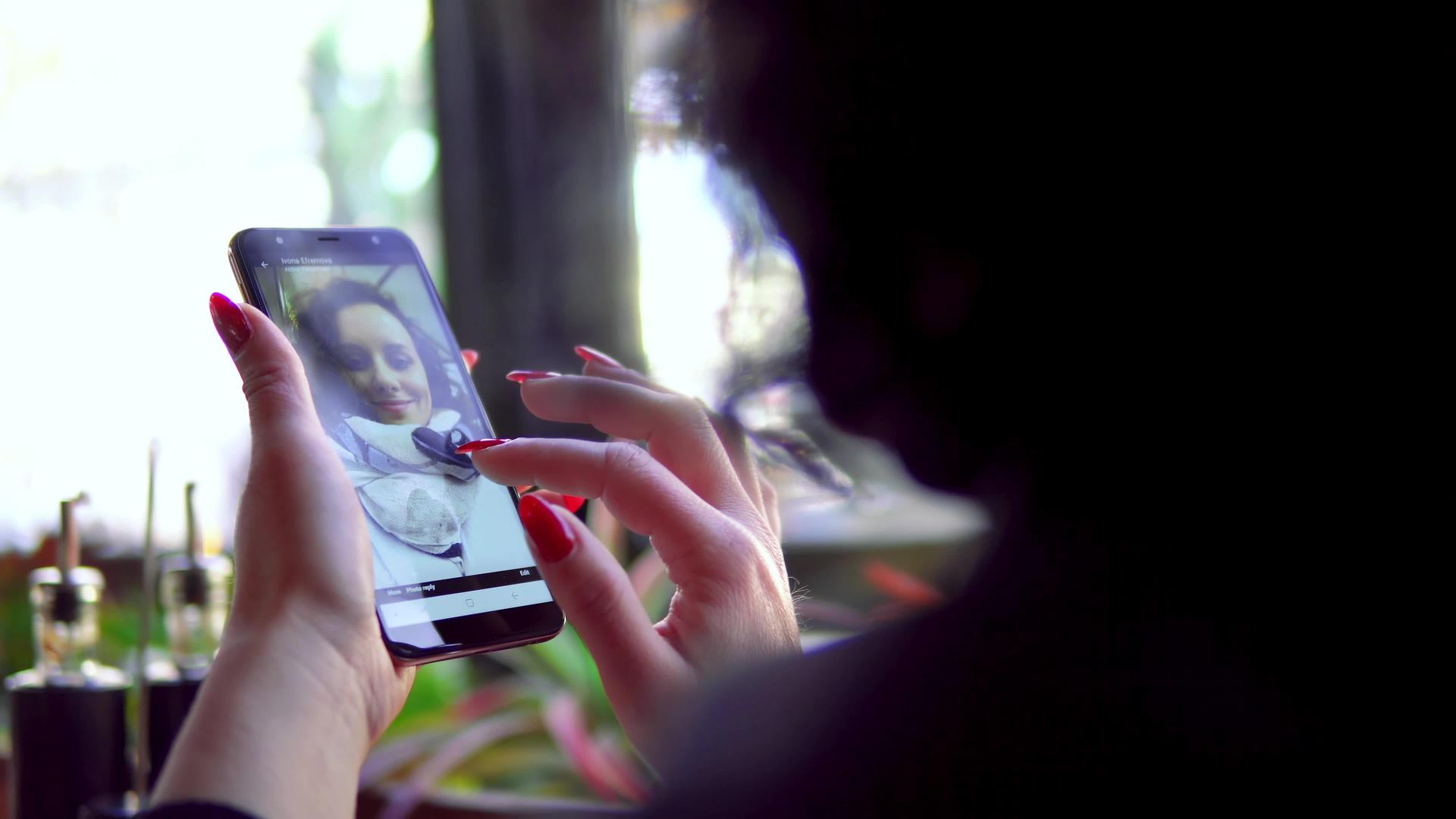 女性用智能手机在画廊上滚动观看女儿模特的照片视频的预览图