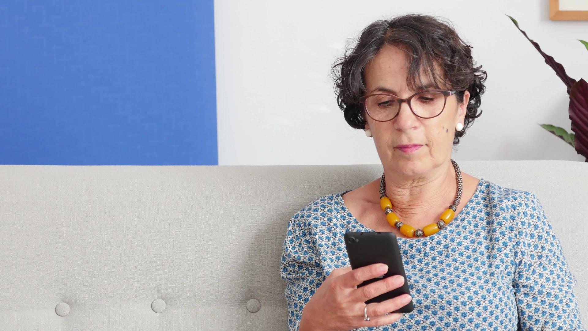 一位资深女性使用智能手机并微笑视频的预览图