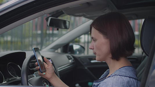 30名女性坐在车里使用手机女司机手持手机在线视频的预览图