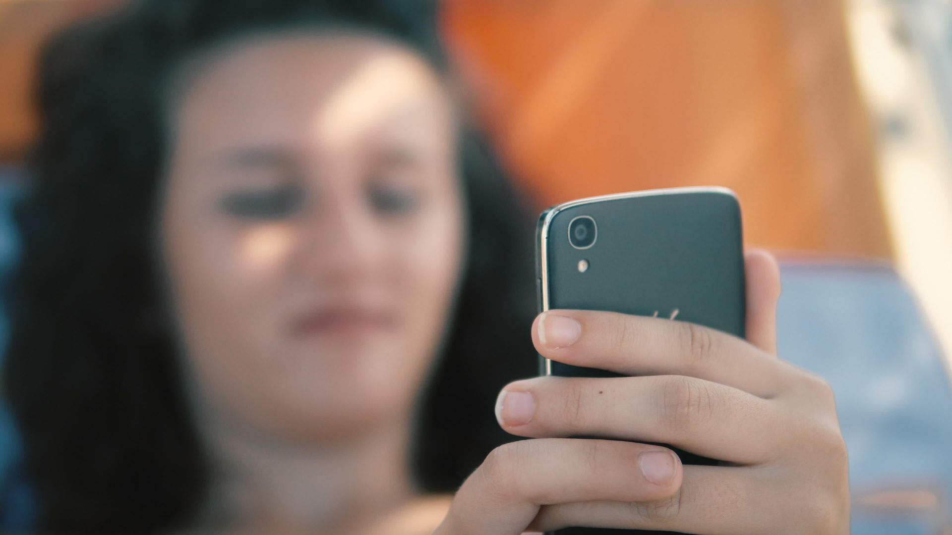 黑发女孩在沙滩上玩智能手机游戏视频的预览图