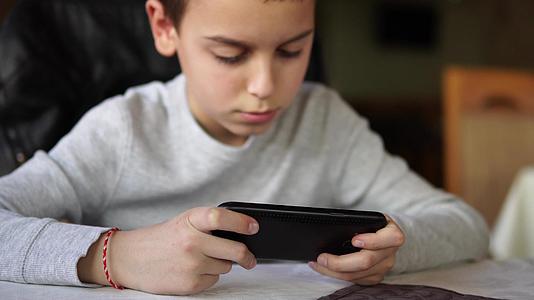 男孩在智能手机上玩游戏视频的预览图