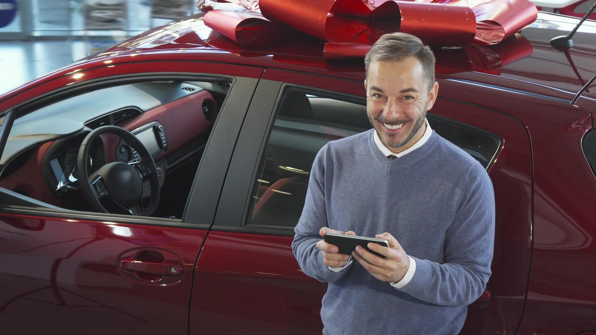 一个微笑的人站在车旁边在电话里打字视频的预览图