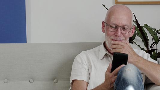 一位老人用智能手机微笑着视频的预览图