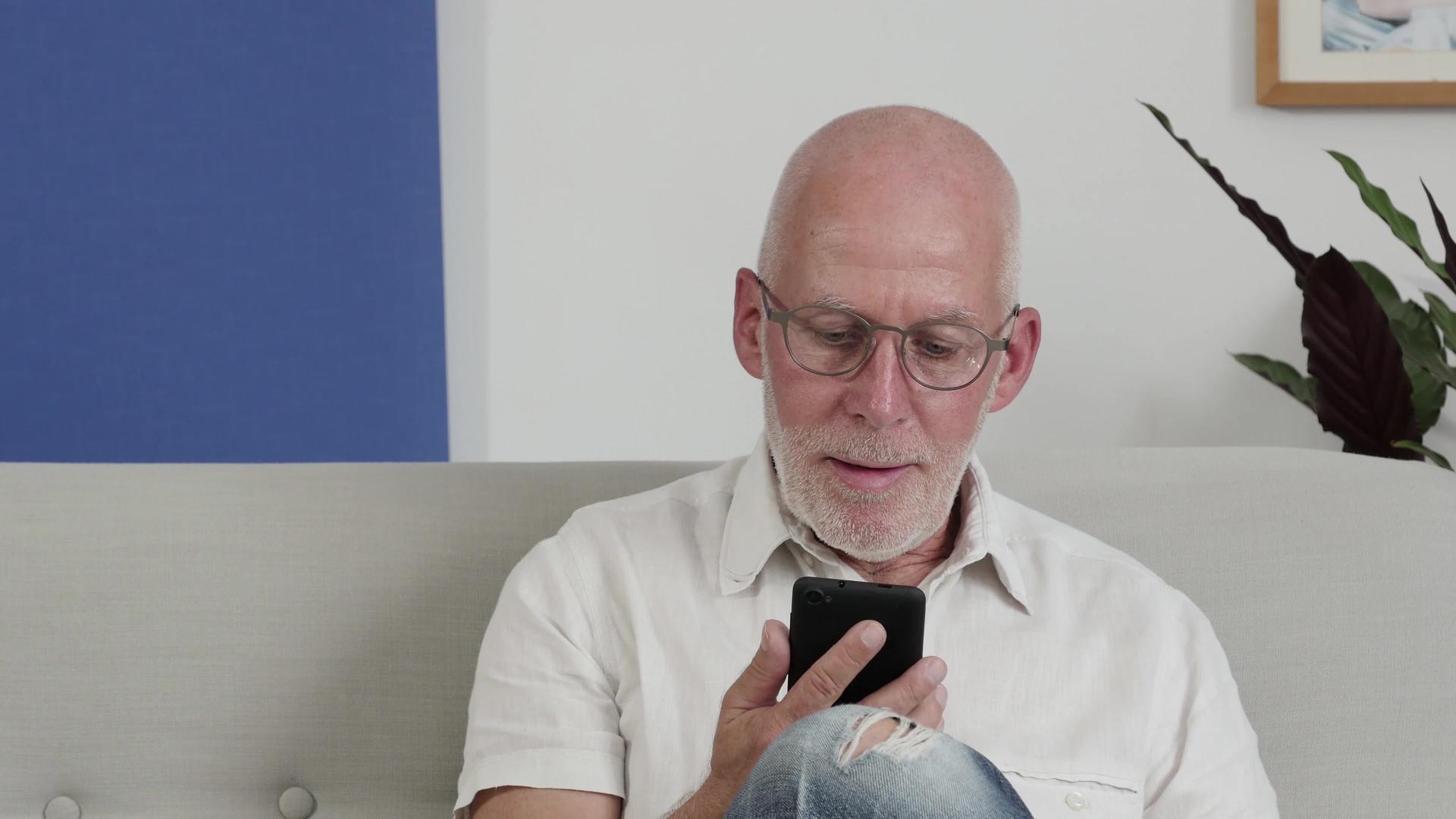一位老人用智能手机微笑着视频的预览图