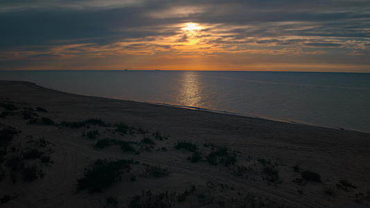 无人机海滩景观与小绿灌木反对明亮的橙色日落视频的预览图