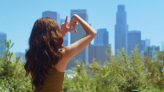 在城市景观视图上未知女孩的手指标志着LA视频的预览图