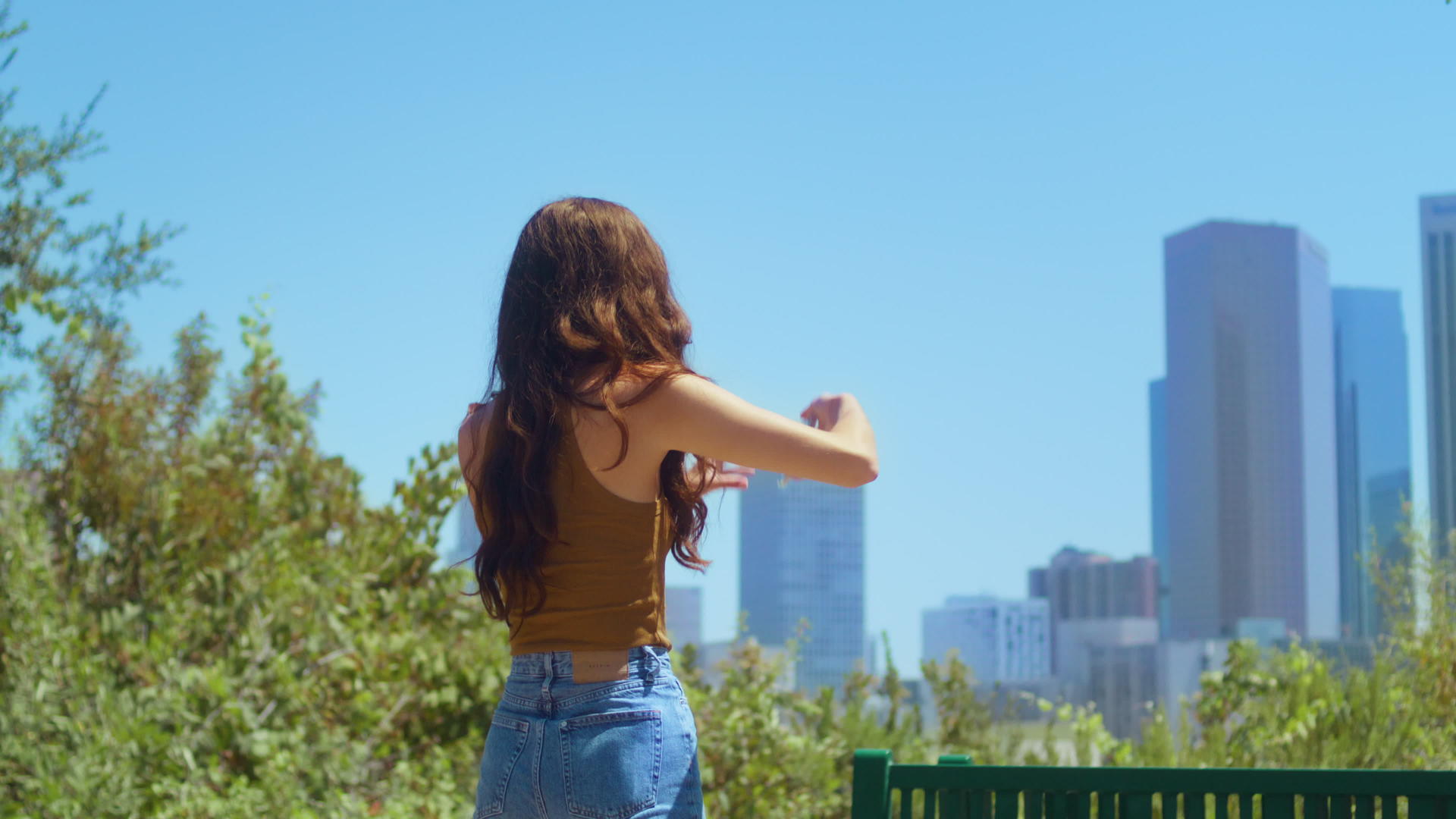 不知名的黑发站在绿色公园的背影上拍照城市景观视频的预览图