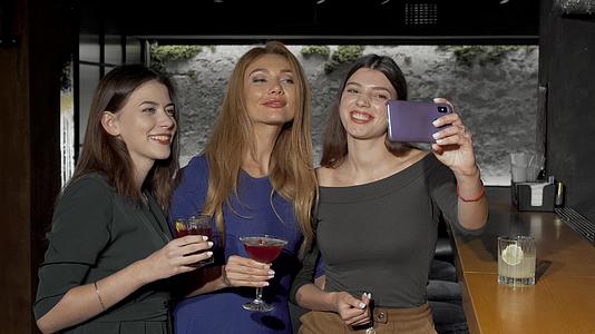 一群女朋友在酒吧用智能手机自拍视频的预览图