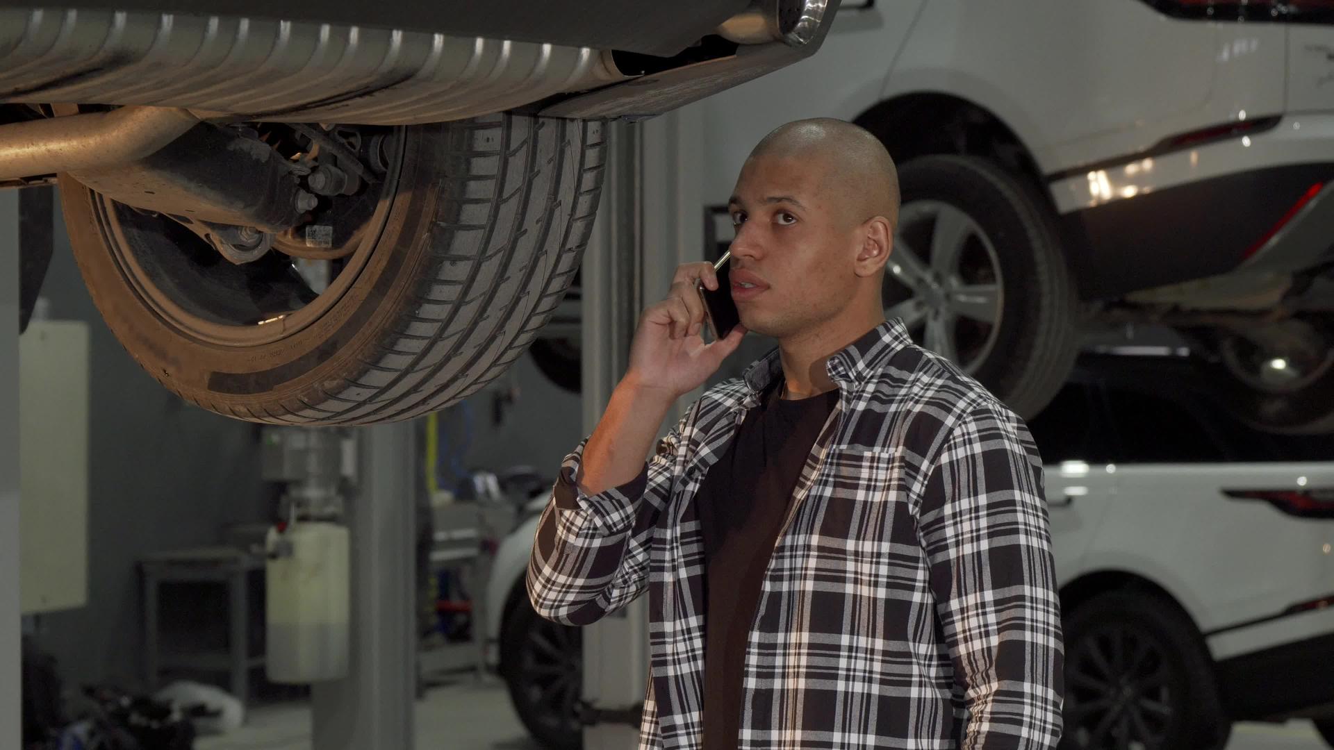 在汽车修理站打电话的非洲年轻男子在电话中讲话视频的预览图