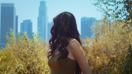 女性回望站在公园里的摩天大楼视频的预览图