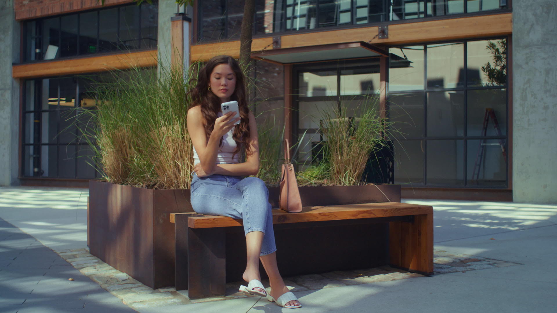 坐在城市长椅上的亚洲黑发女孩打电话视频的预览图