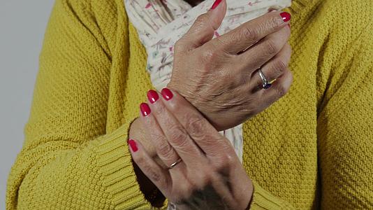 一名身穿黄色毛衣、手腕疼痛的妇女被紧紧地压在一起视频的预览图