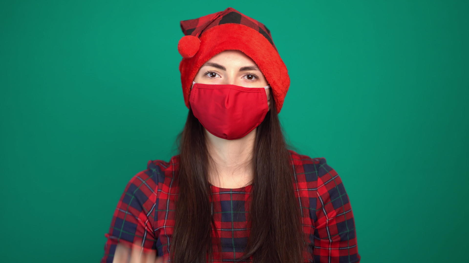 美丽的女人戴着圣诞红帽子和医疗保护面具的肖像显示在她的嘴上视频的预览图
