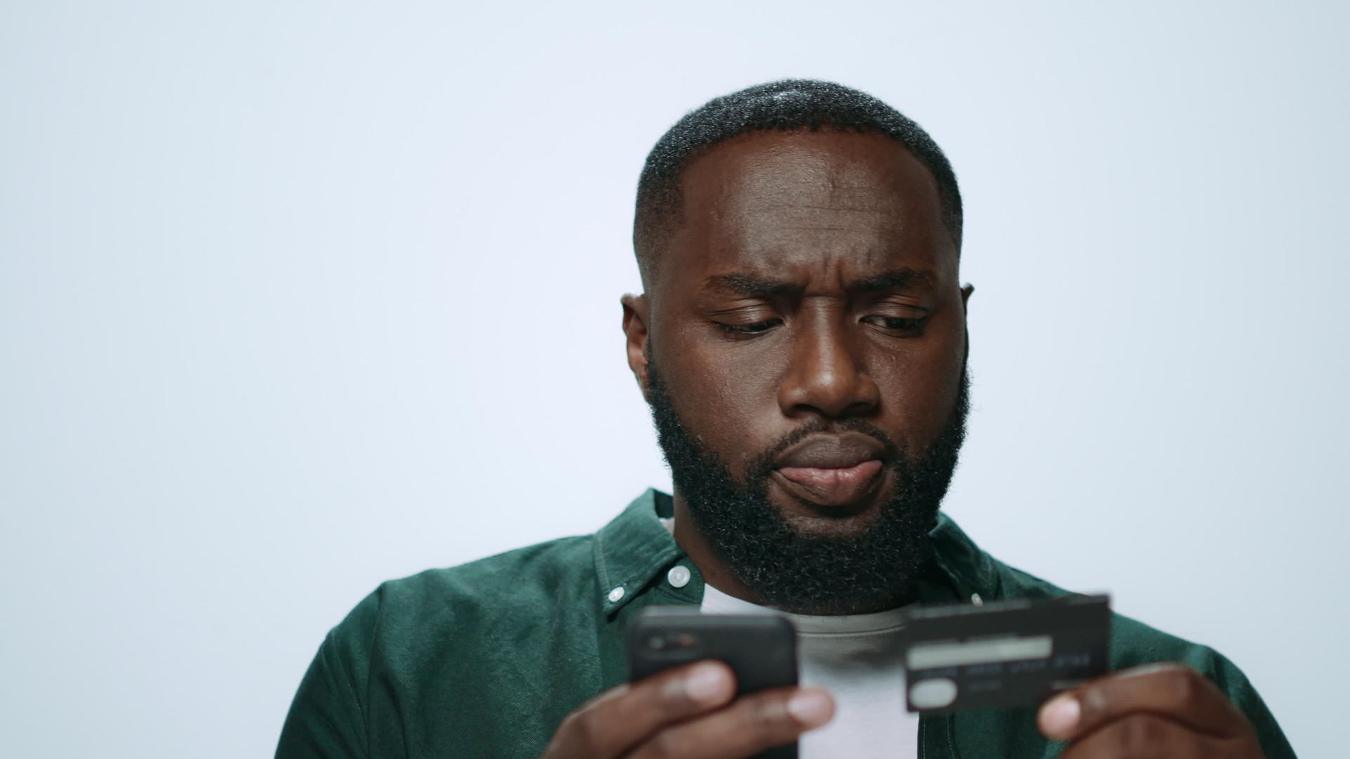 严重的非洲男子在工作室用智能手机在网上购物视频的预览图