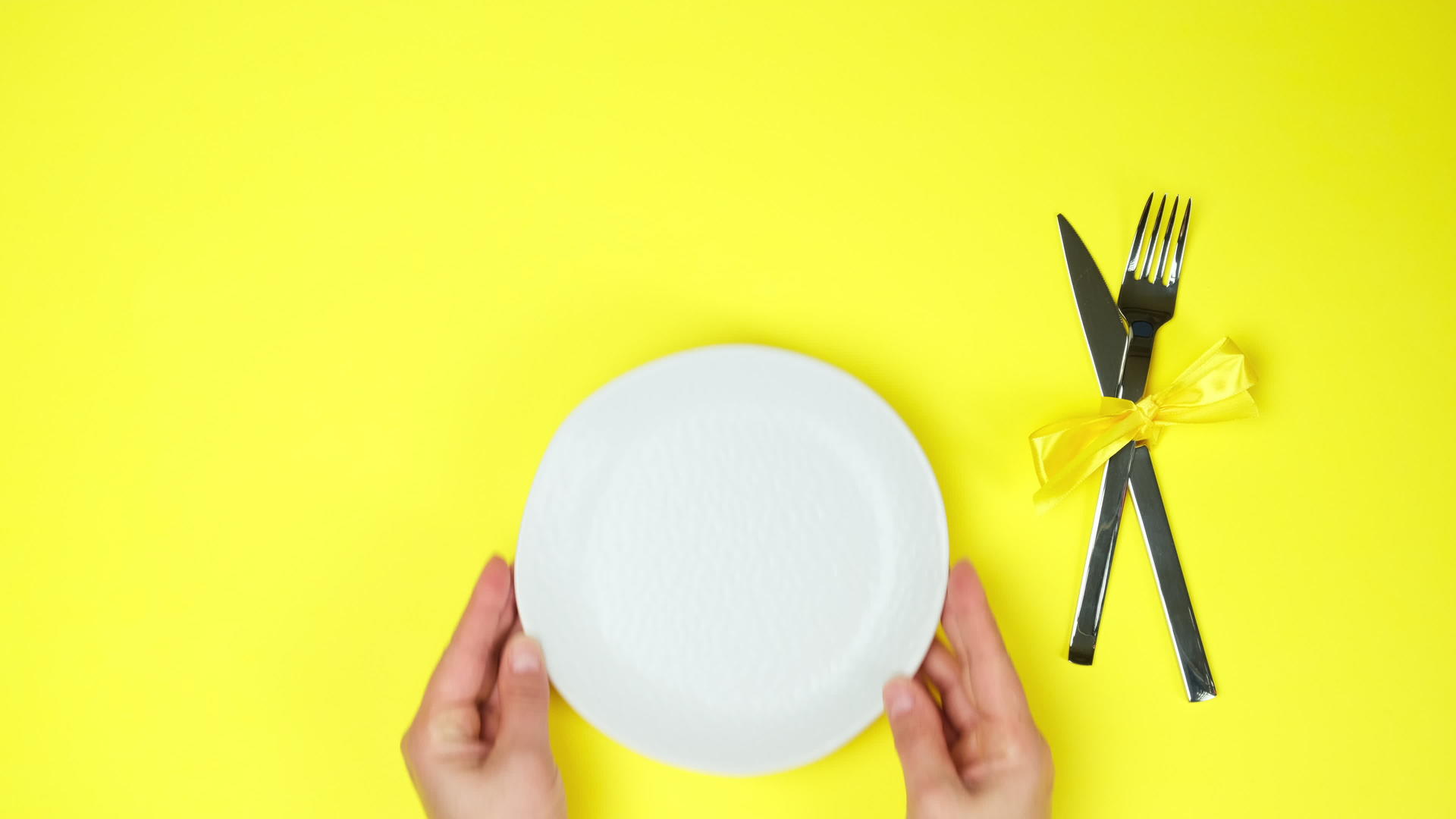 女人用金属刀和叉子把白色的空盘子放在白板上视频的预览图