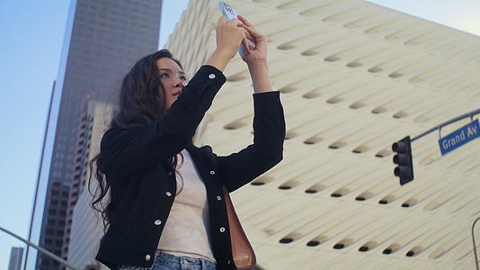 女性游客在智能手机上制作照片街街视频的预览图