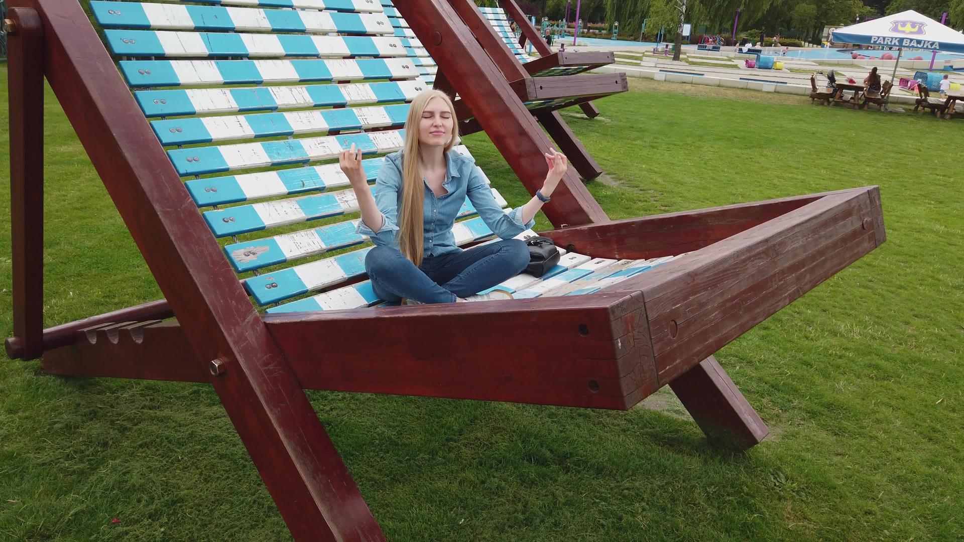 女孩在公园里的一把很大的椅子上冥想视频的预览图