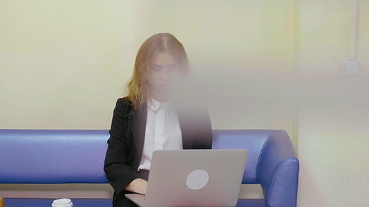 重要的商业女性坐在办公室的沙发上用笔记本电脑工作视频的预览图