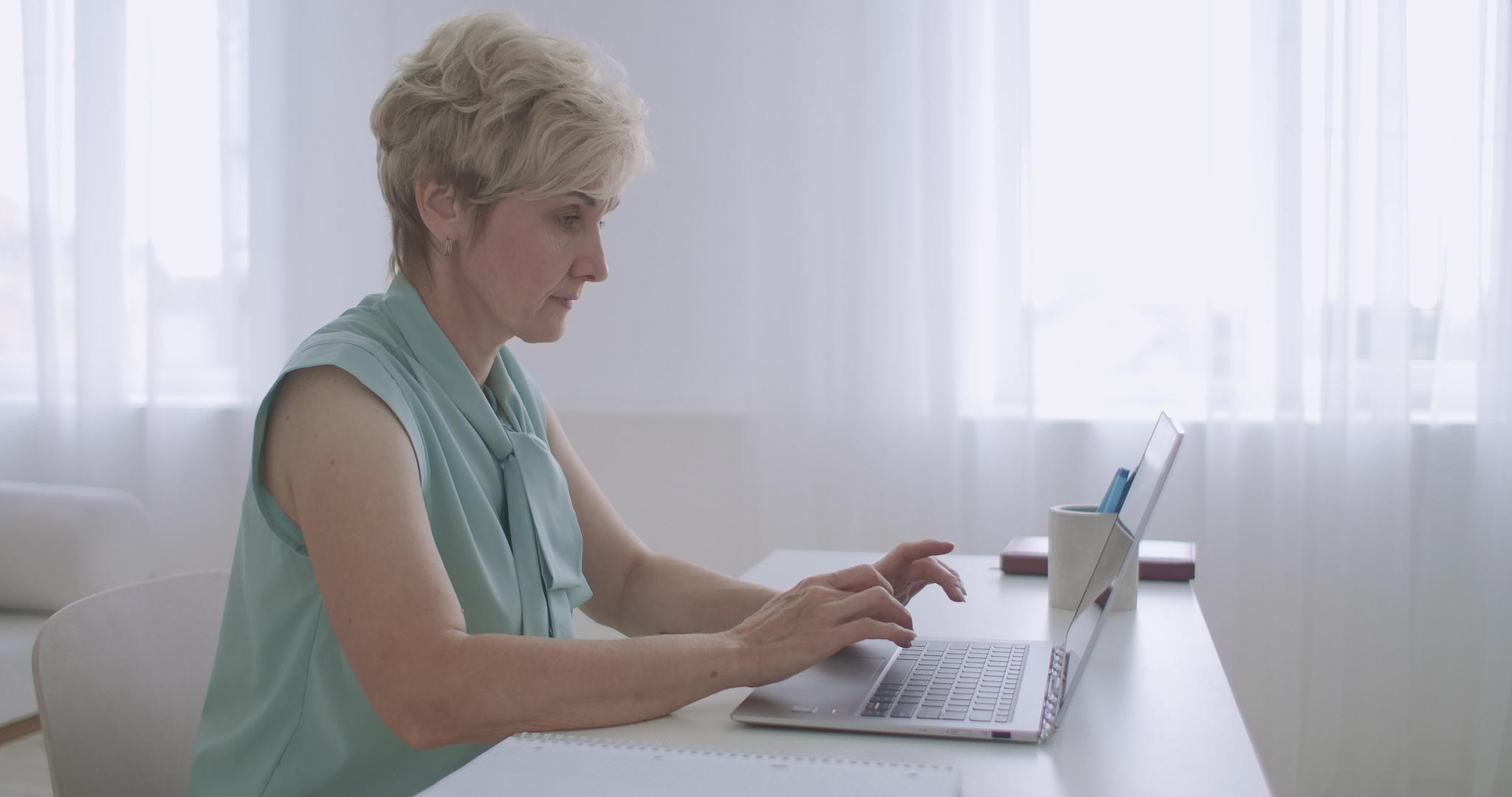 老女秘书正在办公室的笔记本电脑键盘上输入电子文档视频的预览图