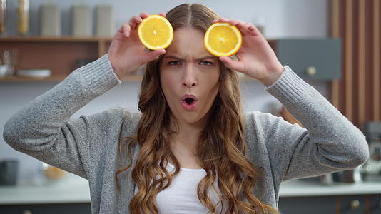 情感女孩在厨房用橘子做面孔视频的预览图