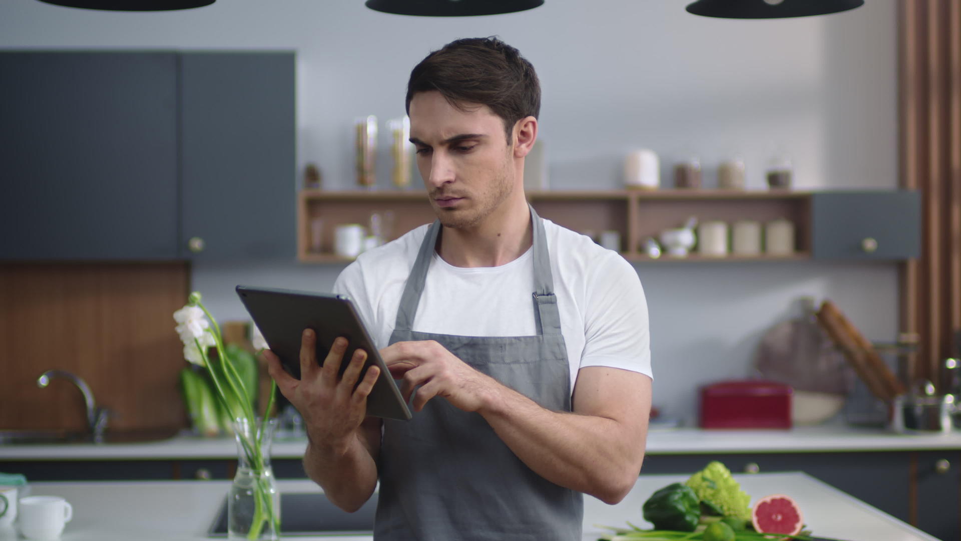 厨师在家庭房间的平板电脑上阅读食谱视频的预览图
