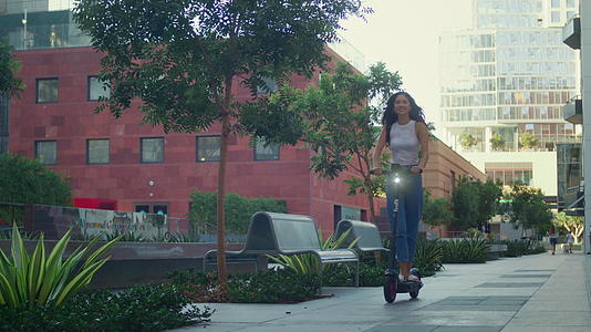 快乐的女人在夏天散步时骑滑板车视频的预览图