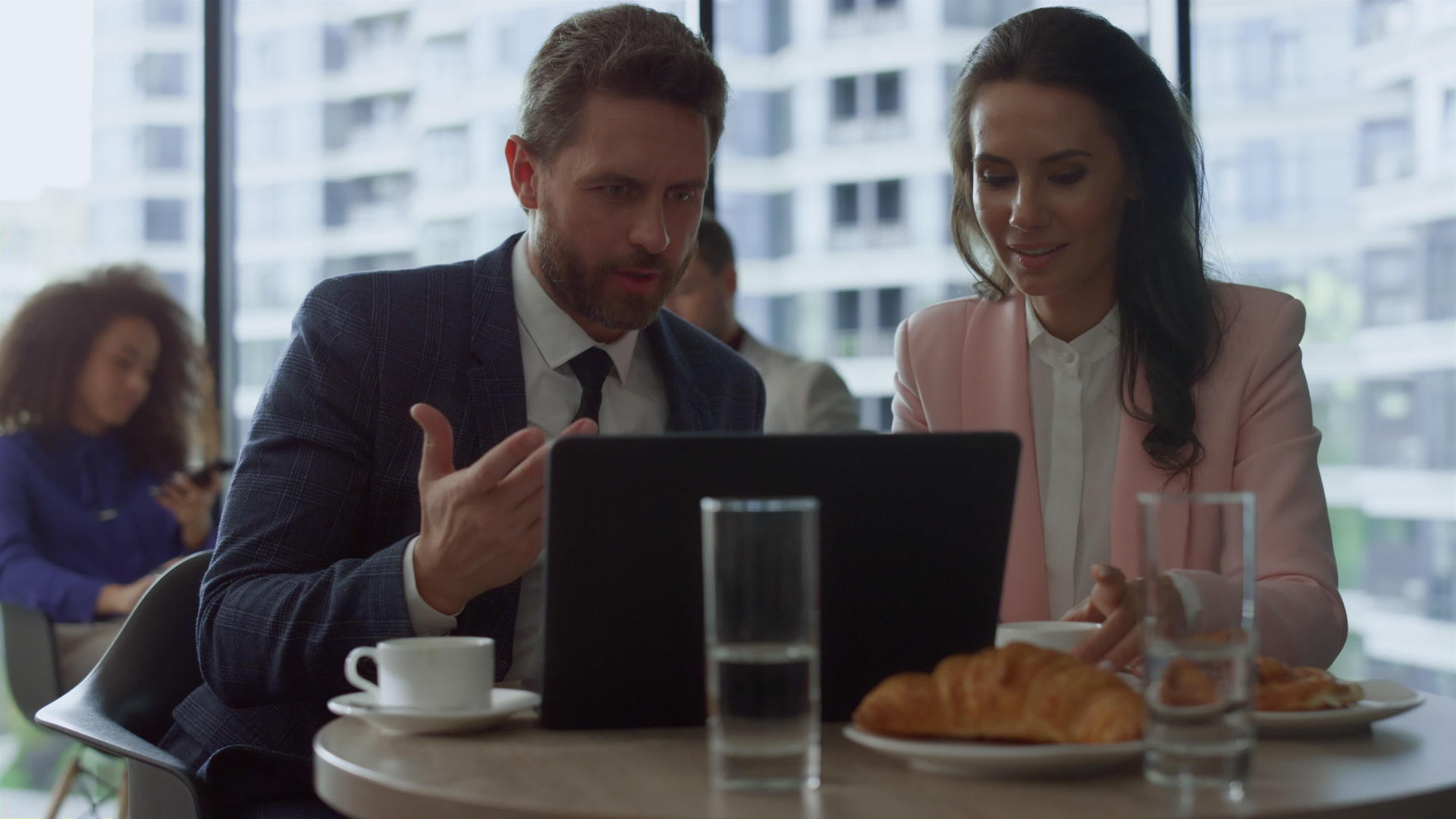 专注的商务人士在咖啡馆讨论使用笔记本电脑进行营销视频的预览图