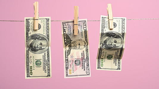 挂在晾衣绳上的美元有一个粉色背景洗钱概念视频的预览图