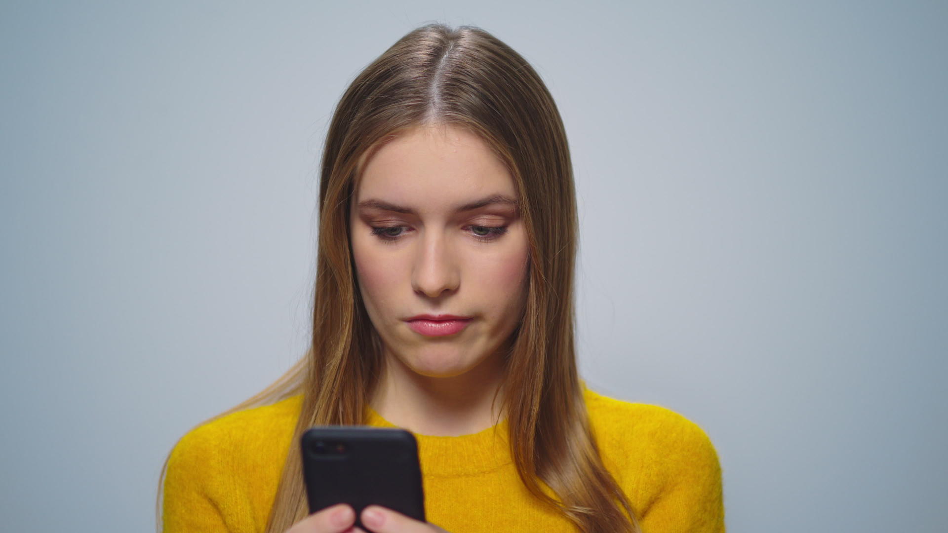 在灰色背景上女子使用智能手机视频的预览图