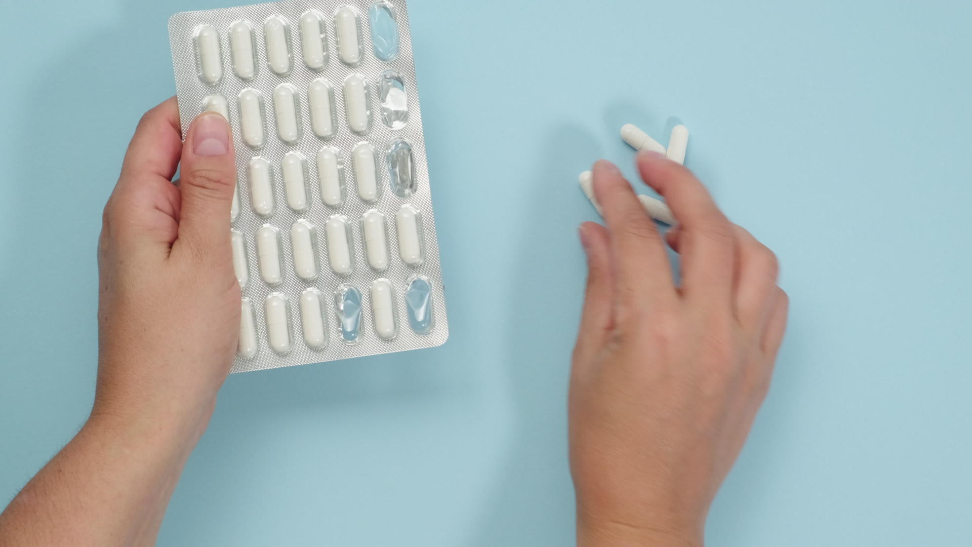 蓝色背景的阴性女性用手折叠奥瓦尔白药片浸泡袋中的药物视频的预览图