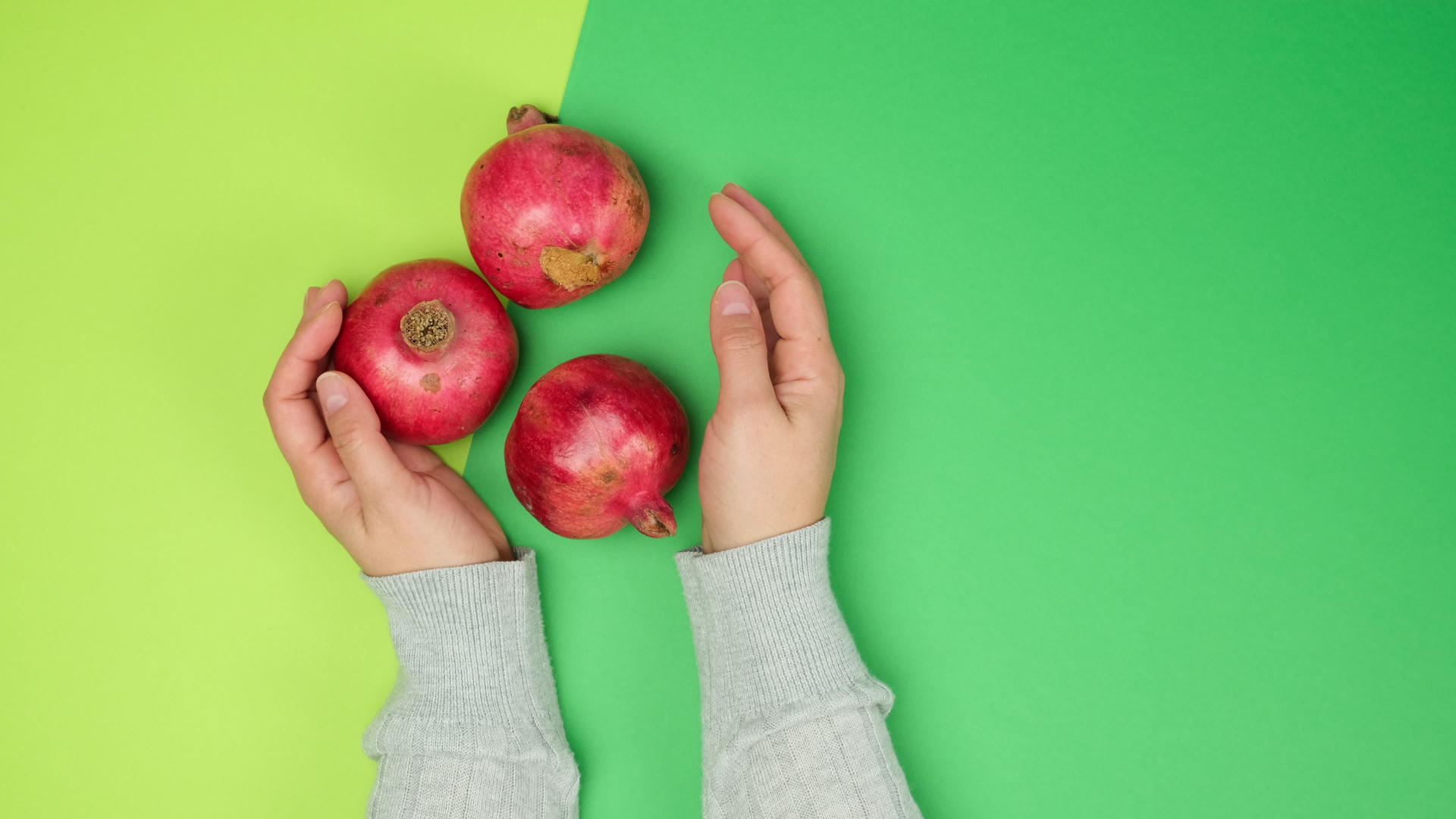 在绿色的背景下双手握着红色的成熟石榴视频的预览图
