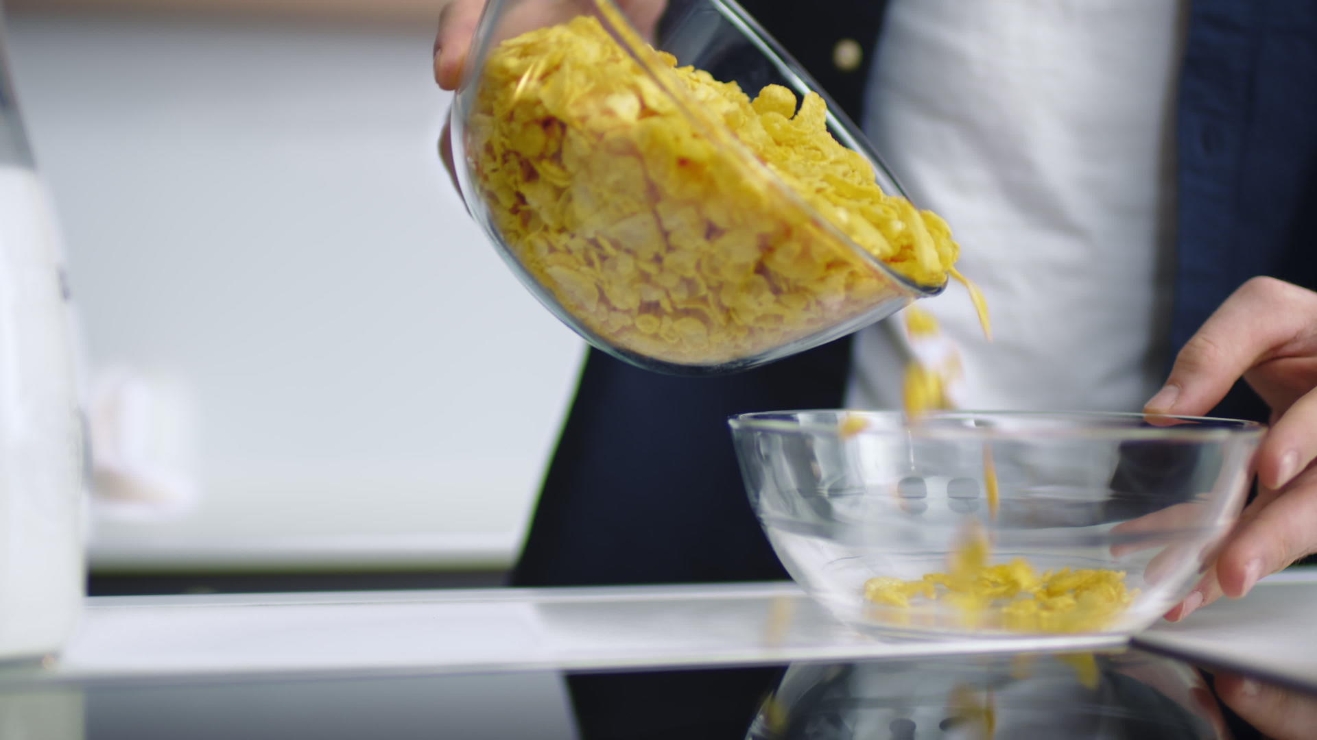 熟人把玉米片倒进厨房背景的玻璃碗里视频的预览图