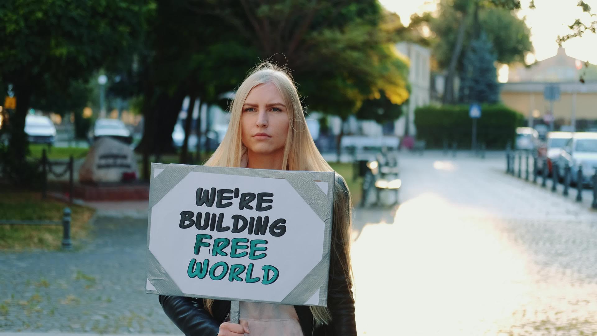 金发金发女人拿着流水器挂着建立自由世界的口号视频的预览图