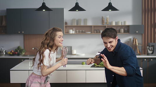 一对幸福的夫妇在家里的厨房里唱歌视频的预览图