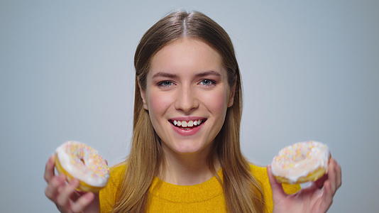 微笑的女性肖像和甜圈玩得很开心视频的预览图