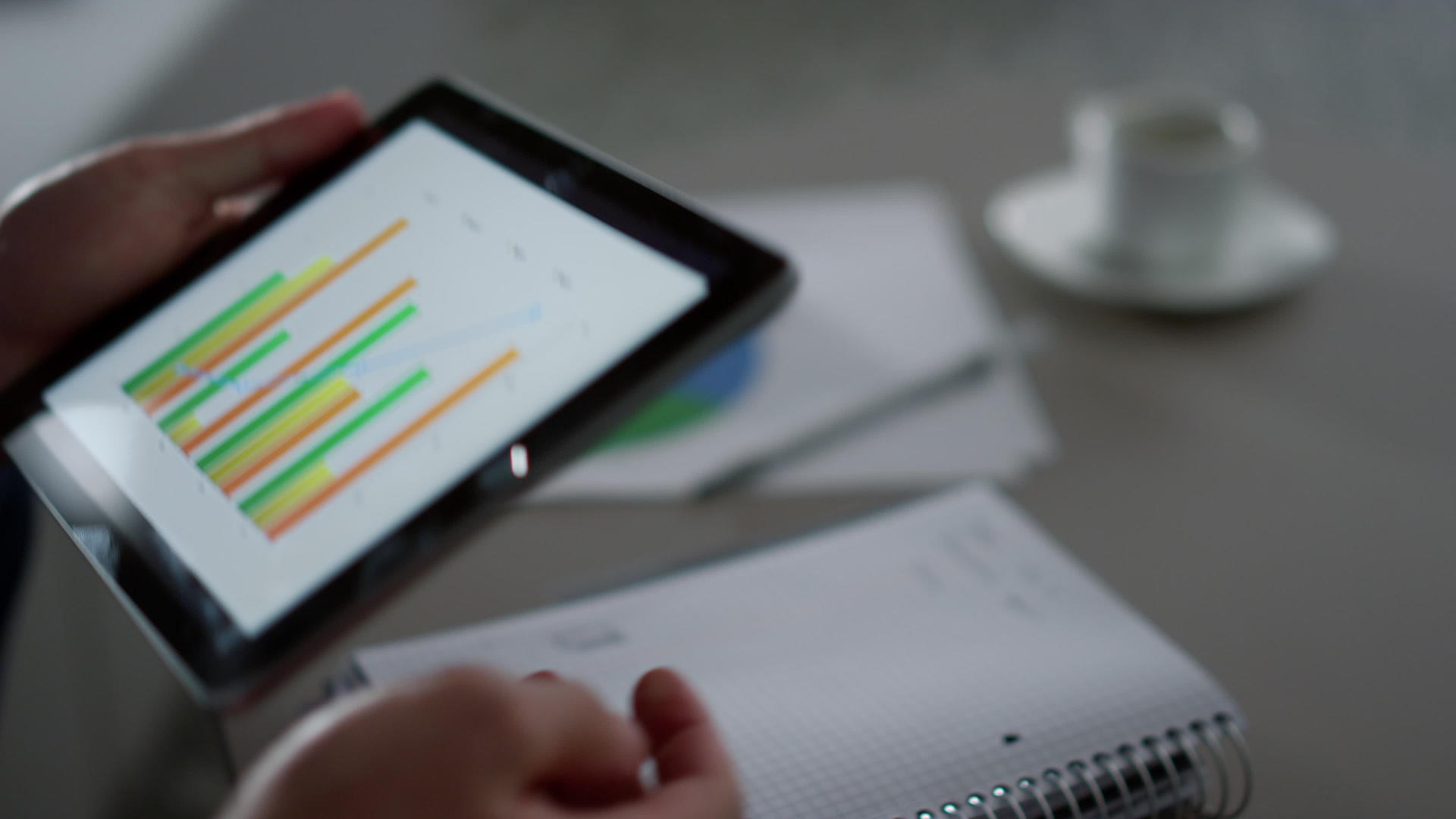管理者使用数字平板设备在家庭办公室咖啡馆编写图表视频的预览图