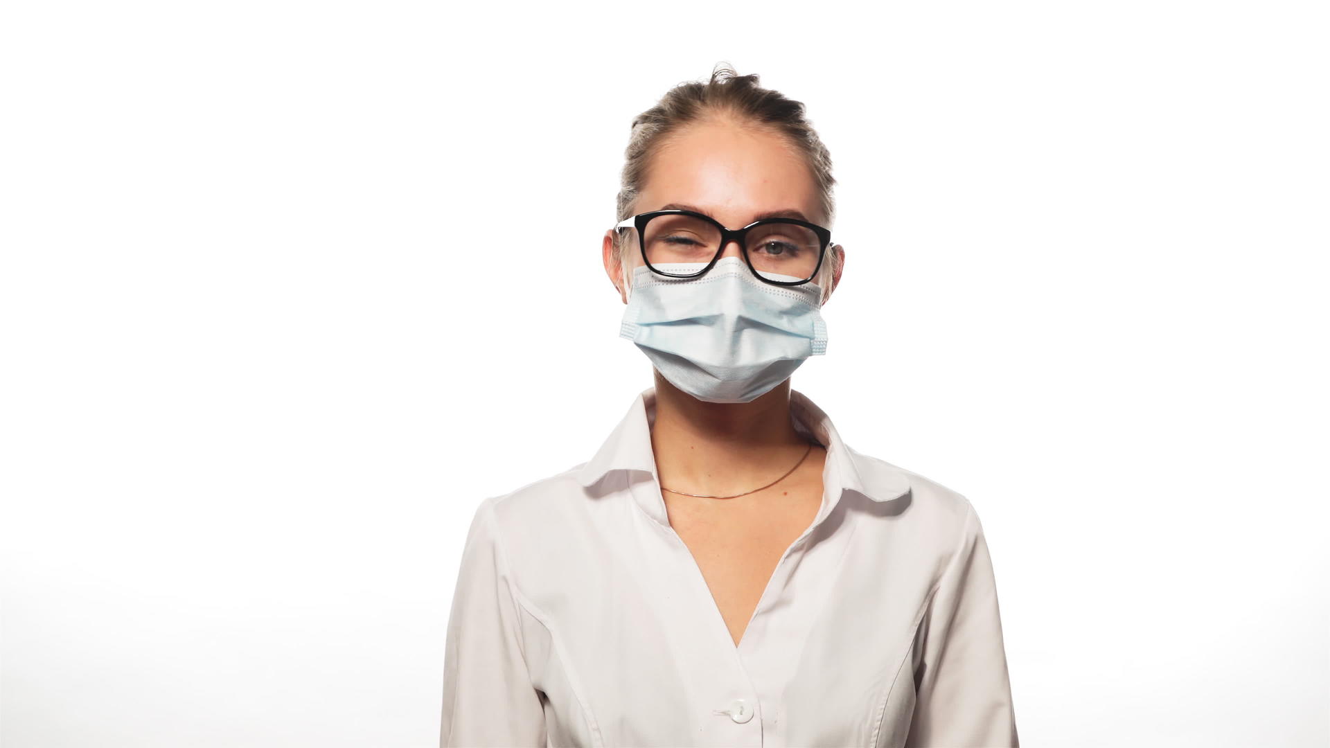 戴着眼镜和医疗面具的年轻护士摇摇头听着白色的镜头视频的预览图