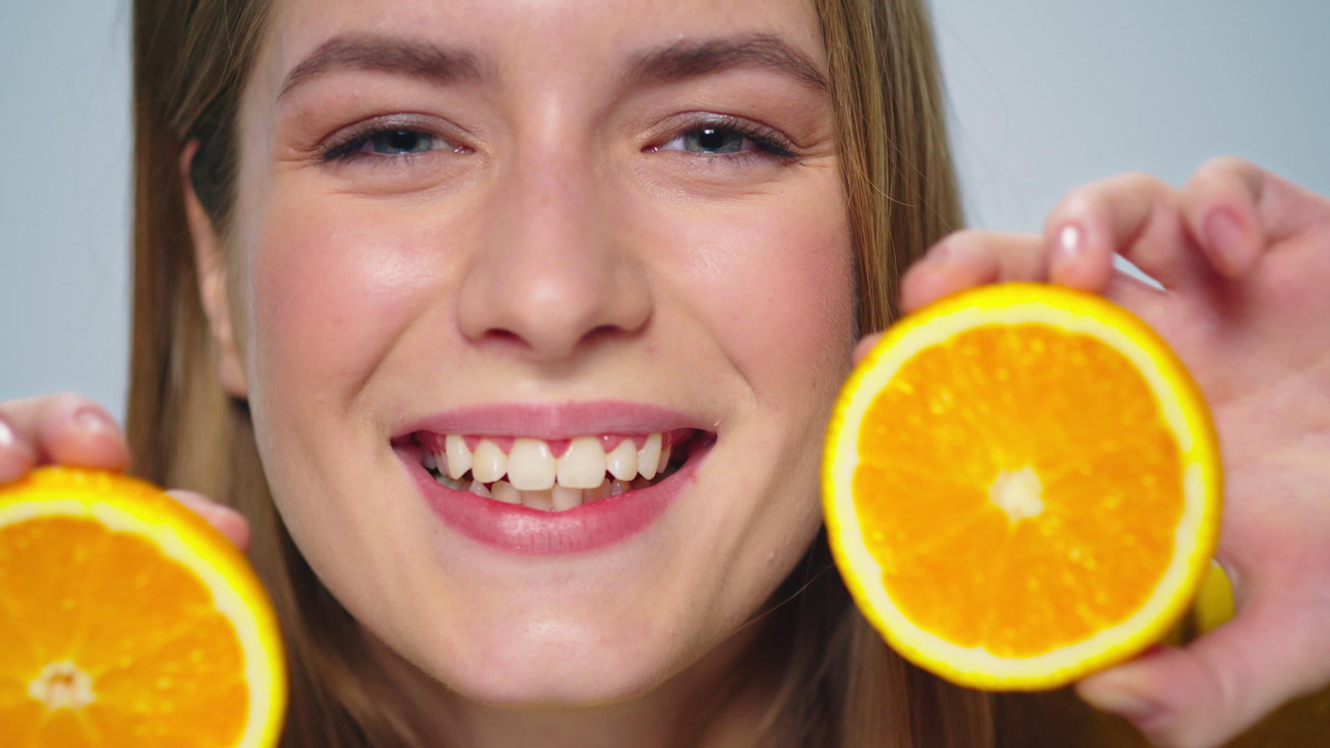 特写一个积极的女人在工作室用手拿着橘子做鬼脸视频的预览图