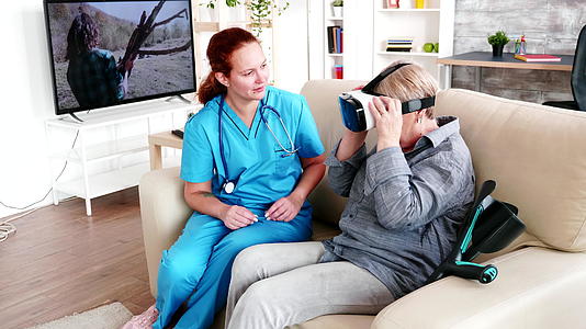 女性护理人员帮助老年妇女体验养老院的虚拟现实视频的预览图