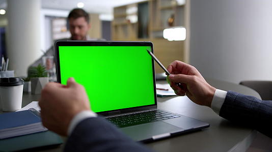 商务人士研究会议桌上的电脑笔记本绿屏视频的预览图