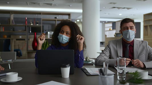 戴着面具的商业团队讨论冠状病毒流行的企业战略视频的预览图
