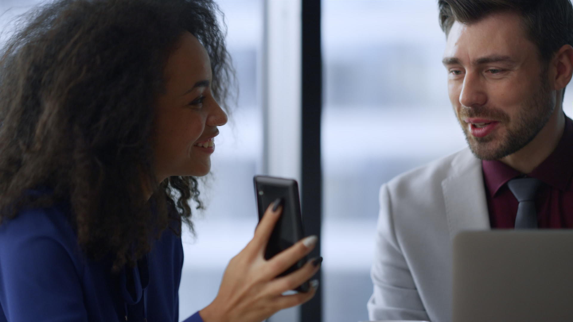 快乐的女商务人士拿着手机和办公室的男同事分享好消息视频的预览图